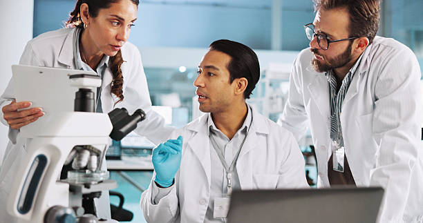 istock Team, scientist and discussion with clipboard in lab for cure discovery, breakthrough or innovation. Science, medical collaboration or people on laptop for test results, pharma research or checklist 2215368660
