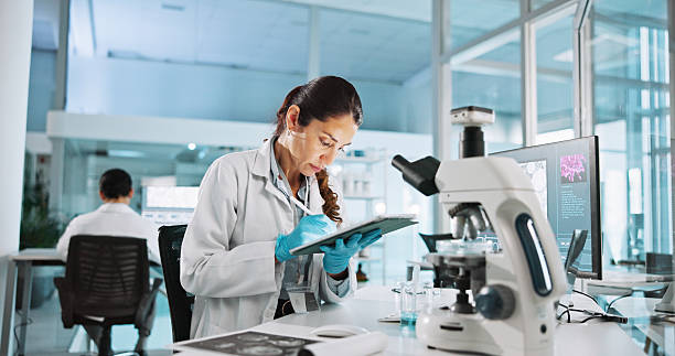 istock Scientist, woman and tablet with study for biology, breakthrough or medical notes analysis. Biotech, laboratory and microscope with DNA research for pharmaceutical RNA or neurology experiment project 2215368666