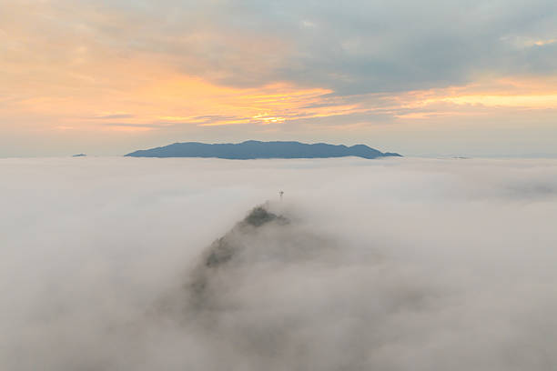 A telecommunications tower stands atop a mountain, emerging from a sea of clouds at sunrise  symbolizing digital connectivity in remote, natural landscapes.