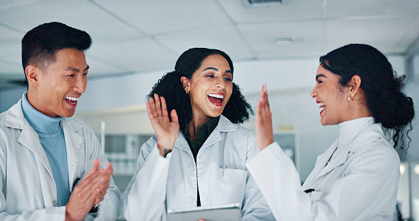 istock High five, teamwork and scientists in laboratory with medical project, discovery and study. Happy, celebration and group of biologists with target for pharmaceutical innovation with collaboration. 2215376669