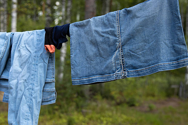 istock Blue denim clothing and socks drying on a clothesline in a forest. 2215376761