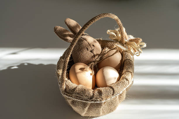 A charming handmade Easter character bunny nestled in a rustic wicker basket with organic farm eggs. The warm natural textures and soft lighting create a cozy and nostalgic atmosphere, perfect for Easter-themed designs, eco-friendly product ads, and seasonal photography