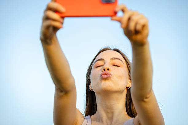 istock Beautiful young lady is taking selfile in nature at sunset. 2215380464