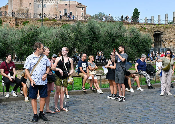 Rome, October 24, 2024, Colosseum: The largest amphitheater attracts many visitors. Among the visitors is a married couple with their blind daughter, who are viewing the monument. The young woman with a cane confidently carries a camera. Other visitors in the background are resting.