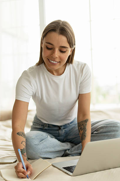 istock Young Woman Working From Home Taking Notes While Looking at Laptop 2215387324