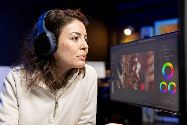 Videographer using editing software while listening podcasts Videographer using editing software to assemble footage into cohesive final result while enjoying podcasts. Specialist color correcting clips while listening music in headphones female film editor stock pictures, royalty-free photos & images