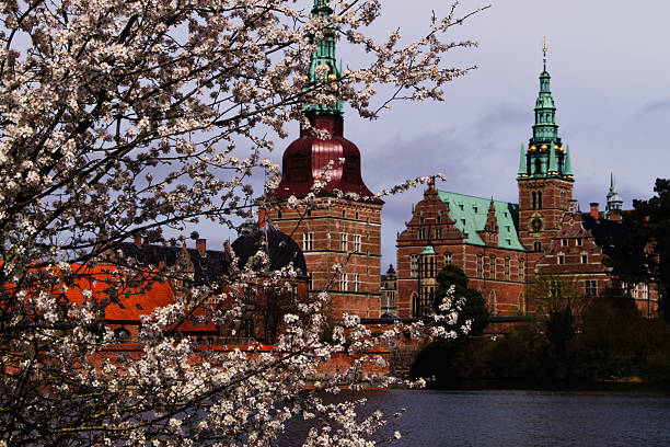 Hillerod, Denmark  - March 26, 2022: View of Frederiksborg castle in Hillerod, Denmark. Beautiful lake and garden with crocuses and daffodils on a foreground