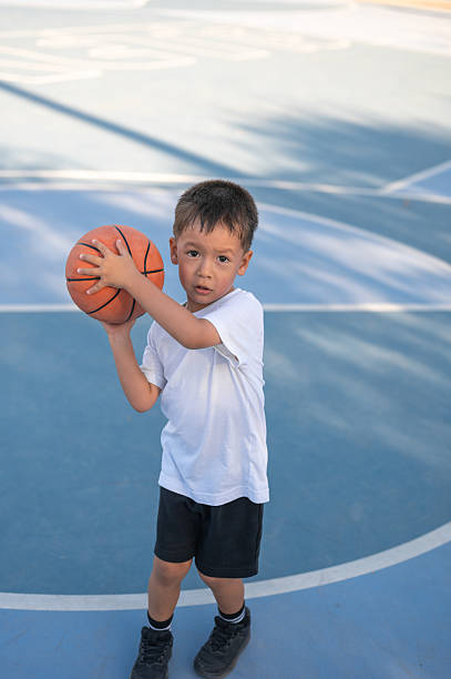 istock Young boy readies to shoot basketball with determined expression. 2215394321
