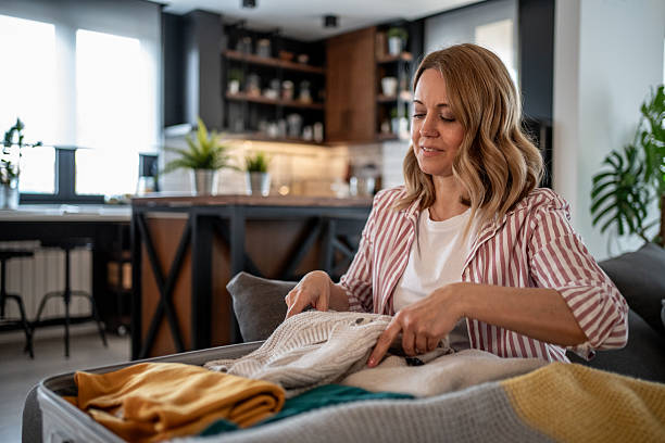 istock Woman packing clothes into suitcase at home getting ready for travel 2215401509