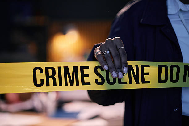 Close-up of person holding crime scene tape, creating a boundary during a police investigation, emphasizing the seriousness of situation, hinting at presence of law enforcement in background