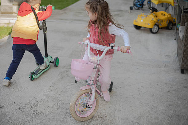 Young children ride bicycles and scooters