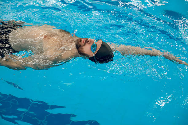 istock Man in black swimming cap swimming backstroke in the pool 2215412058