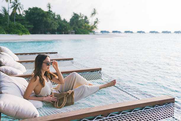 istock Young woman relaxes on sun bed over tropical lagoon 2215412097