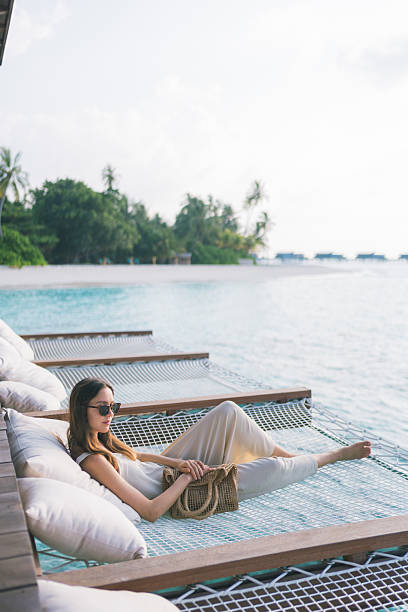 istock Young woman relaxes on sun bed over tropical lagoon 2215412111