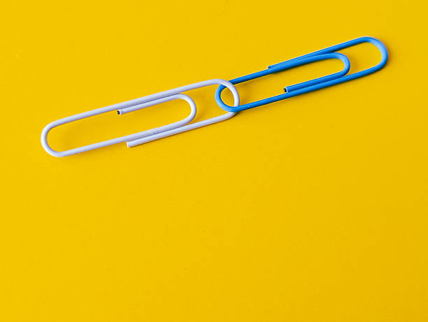 istock two paper clips linked together on bright yellow background 2215412218