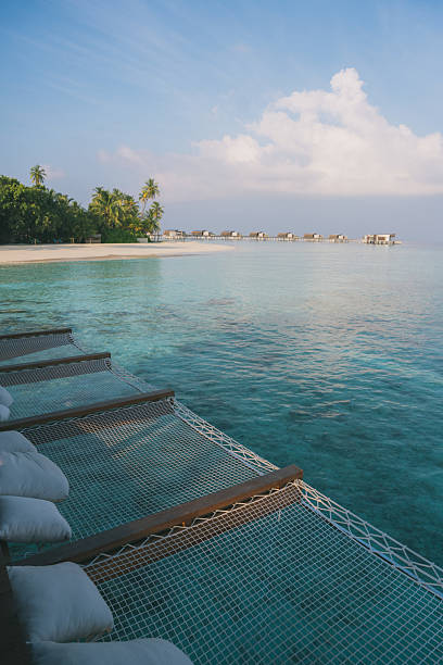 Sun beds in a row over tropical lagoon, Maldives