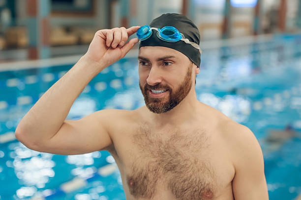 Man in the swimming pool. Confident bearded young caucasian man in the swimming pool