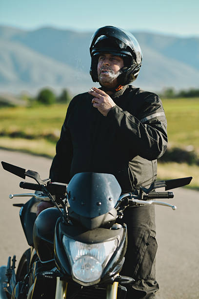 istock Male Biker Smoking Cigarette While Taking Break On Side Of Road 2215414380