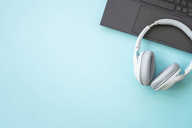 istock Laptop and wireless headphones on blue background. 2215414794