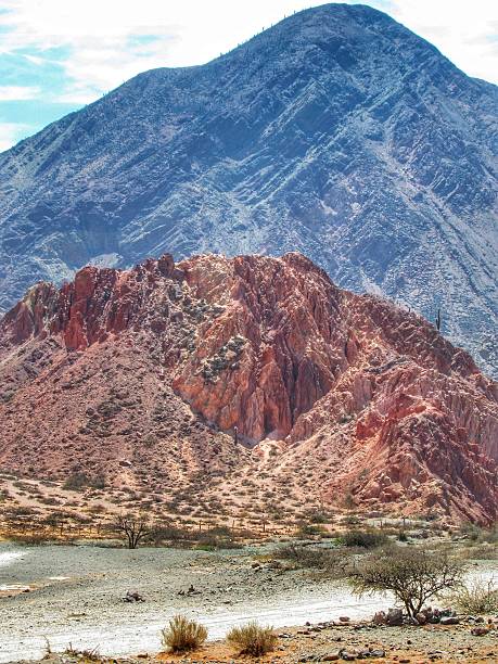 istock Intensely reddish rock formations in direct sunlight, sculpted by time and erosion on the Camino de los Colorados nature trail on a sunny day with blue skies in Purmamarca, Jujuy province, northern Argentina 2215415014