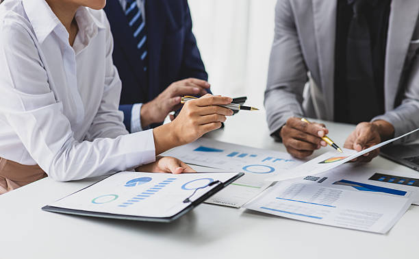 istock Business people analyzing financial documents around table. Business professionals collaborate, analyze financial data, and plan investments in office. 2215416484