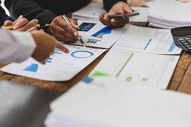 istock Business people analyzing financial documents and using calculator. Business people are working together at the wooden table in the office, using a calculator and analyzing financial documents. 2215416556