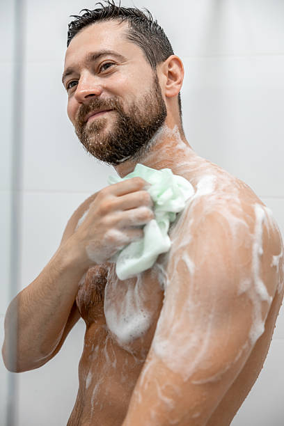 istock Brunette man washing body in white bathroom 2215417590