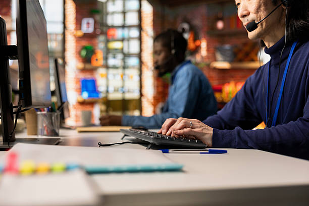 istock Call center agent talking in headset mic, typing on keyboard 2215418269