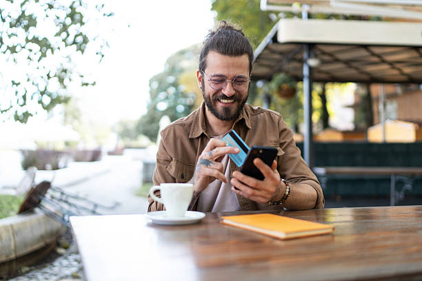istock Young man shopping online using credit card and smartphone at cafe 2215418345