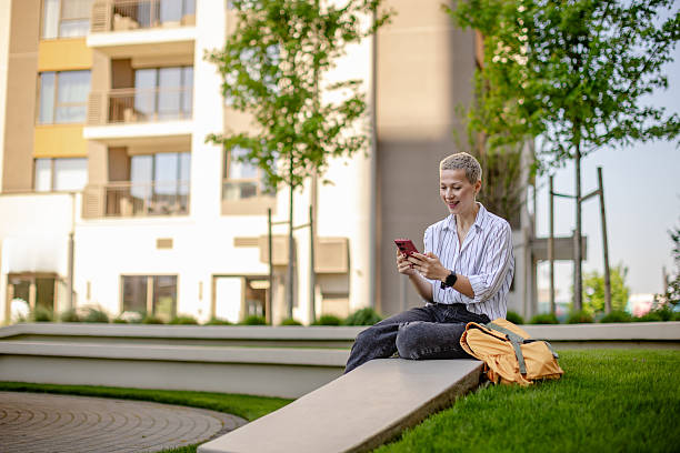 istock Young woman enjoying her time outside while using her smartphone in a beautiful urban park setting 2215418459