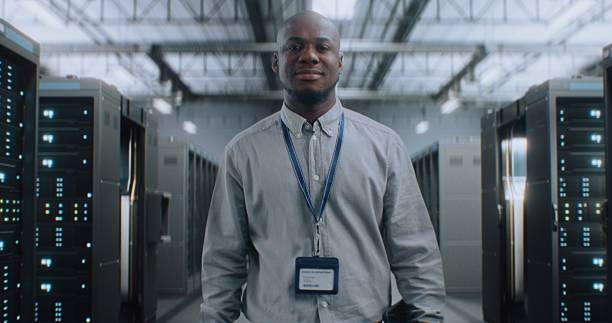 istock Big Data Center with Server Racks: Professional Specialist Walking In Warehouse, Looking at Camera 2215419653