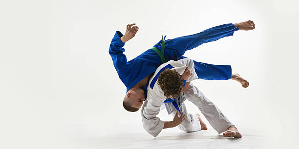 istock Judo practitioners in mid-execution of dramatic shoulder throw, white gi athlete flipping with full body rotation against white background. 2215421579