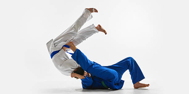 istock Fast-paced throw captured in decisive moment, blue gi athlete sweeping white gi opponent with perfect grip and hip rotation, representing dominance, against white background. 2215421584