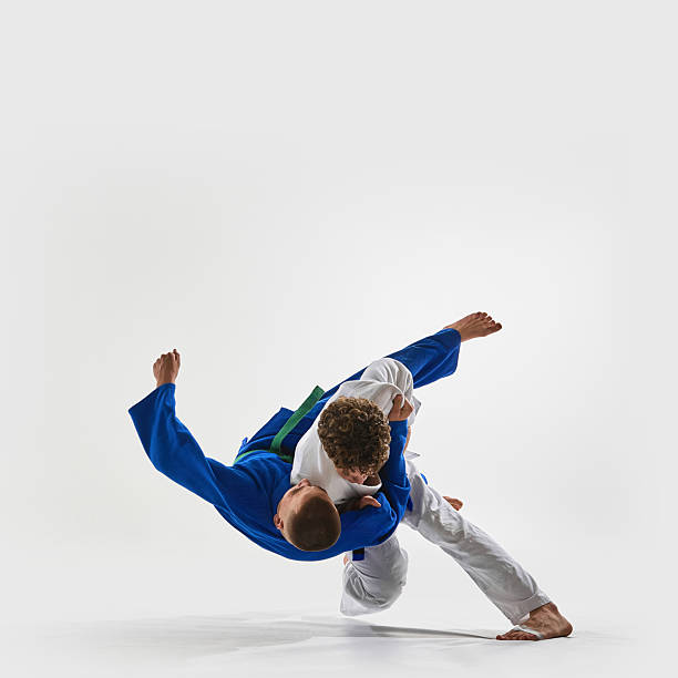 istock High-speed shoulder throw in progress, athlete in white executes flawless lift, blue gi fighter suspended mid-air, representing victory against white background. 2215421603