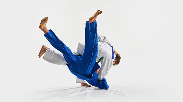 istock Powerful judo throw in motion as blue gi athlete flips mid-air, while opponent maintains grip, symbolizing energy against white background. 2215421604