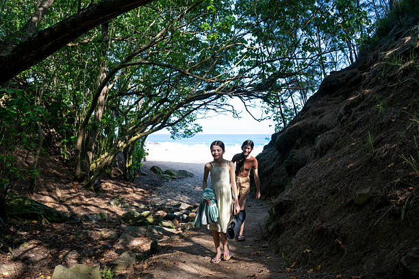 Young girls walk pathway through forest, Mokuleia Beach, Maui