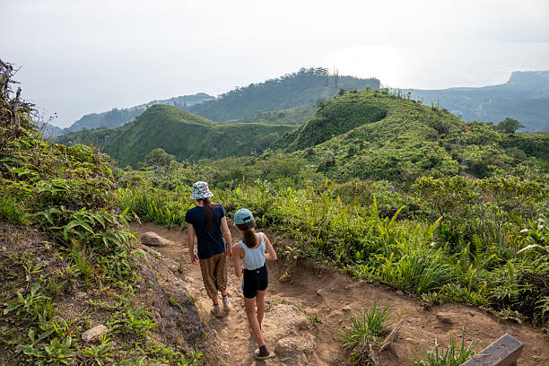 istock Young girls hiking pathway above lush mountains 2215421991