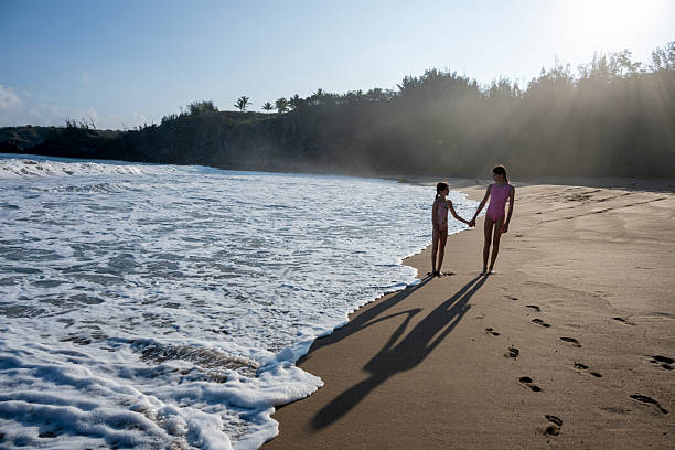 Young girls walk along beach at sunrise, Mokuleia Beach, Maui