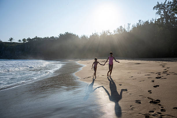Young girls walk along beach at sunrise, Mokuleia Beach, Maui