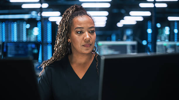 istock Focused IT Specialist Working on Computer in Office Environment. Diverse Multiethnic Female Developer is Using Two Monitors while Writing Code Late at the Night 2215422213
