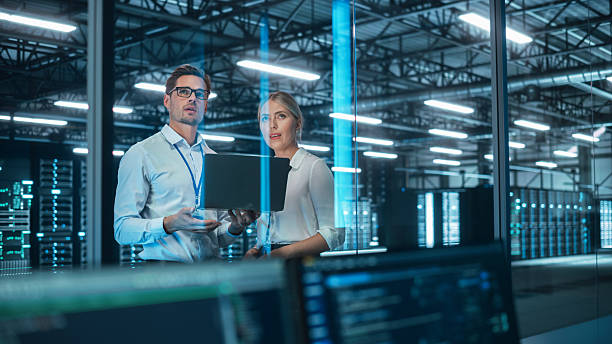 istock Male and Female Server Engineers Work on a Laptop in Data Center. They Look Away and Think About Main Work Tasks. Evening Office. Modern Industry Research and Development Center. 2215422460