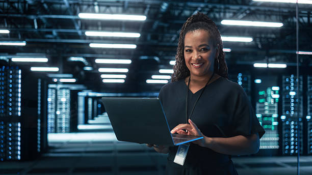 istock Black Female Chief Technology Office Using Laptop Computer, Standing in Big Office Data Center. System Administrator working with SAAS, Cloud Web Services. E-Business Digital Entrepreneur concept 2215423435