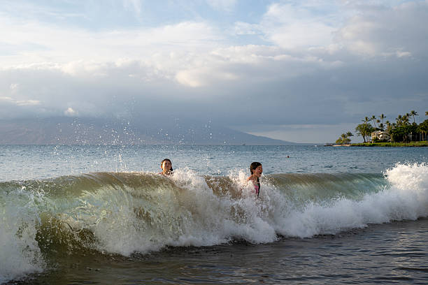 Young girls body surf in waves, Wailea Beach, Maui