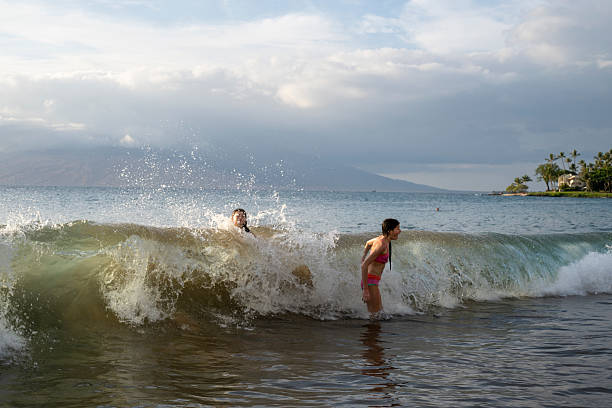 Young girls body surf in waves, Wailea Beach, Maui