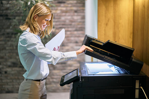 istock Businesswoman making a copy using a modern multifunction printer in the office 2215425327