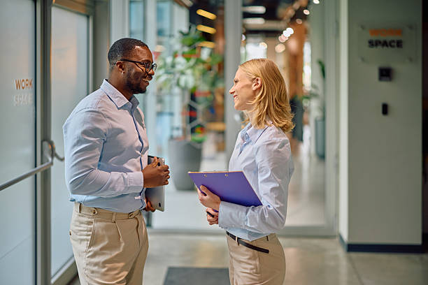 istock Two smiling business people talking in modern office corridor 2215425596