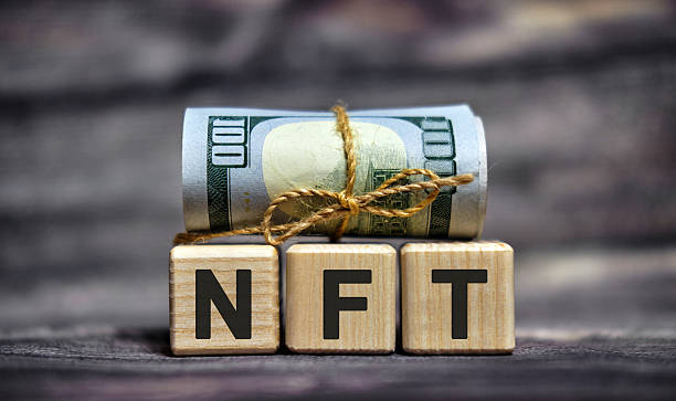 istock NFT - text on wooden cubes with dollars 100 bills 2215427258