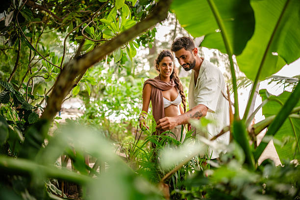 A young couple strolls through vibrant foliage in Thailand, enjoying each other's company and the natural beauty around them during their leisurely vacation.