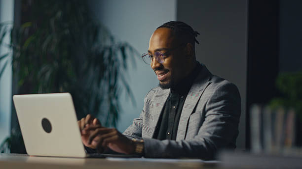 istock Smiling entrepreneur or executive working on laptop in office, engaged in online communication. Concept of digital workflow, leadership, modern business, confidence, and professional success. 2215429293