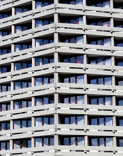 A detailed close-up of a skyscraper facade showcasing rows of balconies arranged in a precise, repetitive geometric pattern. The uniformity and symmetry create a striking architectural texture, emphasizing modern urban design and structural rhythm.